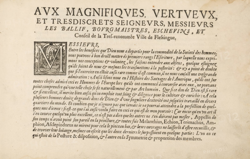 To the magnificent, virtuous, and discreet lords, Dedication to the bailiff, mayors, aldermen and council of the city of Vlissingen, page 1 of 2, The Magazine or House of the Loyal Penmanship, album page, text sheet, Text sheet with a dedication to the bailiff, page 1 of 2. The text begins with a historiated initial M. The text sheet is part of an album., writer (clerical worker): David Roelands, Flushing, 1617-01-03 - 1616-01-03, writer (clerical worker), paper, letterpress printing, woodcut, text in letterpress, height 225 mm x width 335 mm, initial, Aged paper with dark printed lines of ornate typography at the top and a block of dense printed paragraph text below, featuring a large decorative initial square containing an illustrated scene with curved lines and a stylized letter shape, faint spots and discoloration scattered across the page, and even margins of blank space surrounding the printed area.
