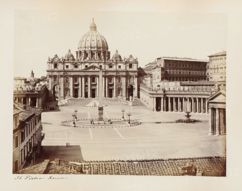 View of St. Peter's Square and St. Peter's in Rome, Italy, St Pietro. Roma, album page, photograph, This photo is part of an album., Rome, 1870 - 1890, photographer, paper, albumen print, height 207 mm x width 268 mm, square, circus, church (exterior), Vatican City, St. Peter's Basilica, St. Peter's Square, A wide plaza with a central circular area surrounded by short posts and lamp standards sits in front of a large ornate building with a tall domed roof and symmetrical facade featuring columns, pediments, statues, and multiple arched doorways; an obelisk rises from the center of the plaza and decorative lampposts are arranged around it, while colonnaded walkways extend from the main building on both sides and a row of buildings with tiled roofs and windows lines the foreground and left edge of the image.