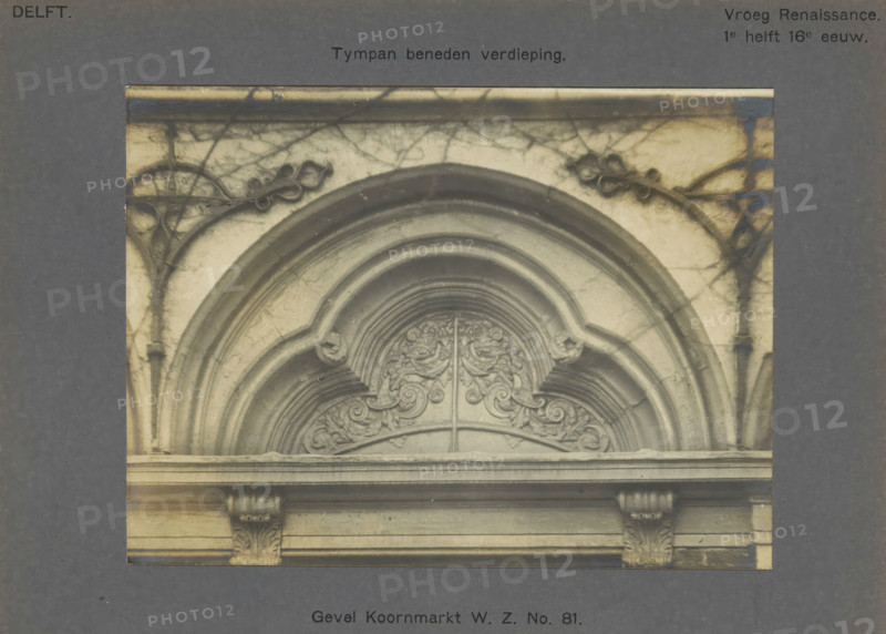 Facade Koornmarkt WZ No. 81. Tympan ground floor, Decoration on the facade of a house on the Koornmarkt in Delft, depicting a niche with leaf motifs, photograph, inscription: 'The right of reproduction of these photos is reserved by the Publisher.', number: '29', inscription: 'Delft. Early Renaissance. 1st half of the 16th century.', Delft, c. 1900 - c. 1904, photographer, paper, pasteboard, gelatin silver print, gelatin silver development, height 117 mm x width 158 mm, ornament derived from plant forms, urban housing, ornament derived from architectural details, Koornmarkt, A close-up view of an arched stone architectural element set within a rectangular frame, showing curved moldings and layered semicircular arches with ornamental carved foliage and scrollwork in the central archway, flanked by vertical pilaster-like structures with carved capitals and horizontal ledges, all rendered in grayscale tones with visible surface texture and faint cracks.