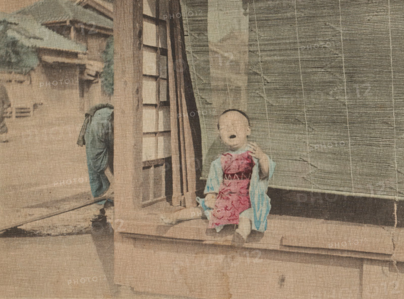 Mamma!, Crying Little Child, page, photomechanical print, c. 1891 - in or before 1896, collotype process, height 134 mm x width 173 mm, toddler (male), crying, shouting, Japan, A faded photograph showing a small child sitting on a wooden step in front of a door with a slatted screen beside it, the child wearing a patterned garment over a lighter robe and sandals, an adult figure partially visible walking away on a street with traditional buildings and tiled roofs in the background, all rendered in muted, aged colors with visible paper texture and signs of wear.