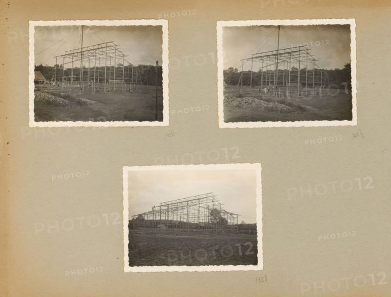 Skeleton construction, album page, photograph, Loose album page with three photos of the steel skeleton construction for an industrial hall. Part of a photo album with photos of machines and structures of the NV Machinefabriek Braat in Surabaya, Sukabumi, and Tegal from the period 1931-1937., Java, 1931 - 1937, photographer, paper, pasteboard, gelatin silver print, developed gelatin silver print, height 85 mm x width 110 mm, height 250 mm x width 320 mm, Person, NV Machinefabriek Braat, making the carcass (, building activities), economic history, overseas history, company history, Period, A beige album page shows three attached sepia photographs with scalloped white borders, arranged with two near the top and one centered below; each photo depicts a skeletal metal framework of a large structure on a flat dirt area with piles of rocks in the foreground and trees along the horizon, thin cables angling down from a tall central mast, and small groups of people and scattered equipment near...