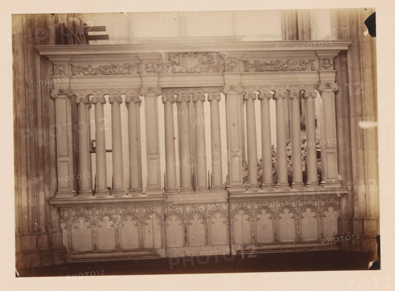 Choir screen in the Dom of Utrecht, photograph, annotation: 'Domkerk te Utrecht, Afsluiting hek, Sept 1891', annotation: 'Utrecht', Dom of Utrecht, 1891, photographer, Utrecht, Attributed to, paper, pasteboard, albumen print, albumendruk, height 170 mm x width 238 mm, parts of church interior: choir, A section of an ornate stone balustrade with a row of vertical columns topped by carved capitals and a profiled horizontal entablature, decorative frieze panels with sculpted foliage and cartouche motifs above, and a patterned lower panel of pointed arch shapes and tracery, flanked by larger vertical pilasters and set against tall stone wall surfaces.
