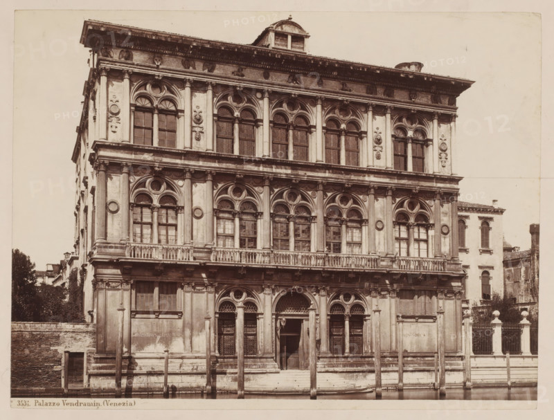 View of the Palazzo Vendramin in Venice, Italy, Palazzo Vendramin (Venezia), photograph, number: '6', inscription: 'I', collector's mark: 'RICH SCHOOL FOR ART HANDBOOK, GROUP', number: 'No. 3531.', inscription: 'Venice pal. Vendramin Calerghi', photographer: attributed to Giorgio Sommer, Venice, 1857 - 1914, Giorgio Sommer, photographer, Attributed to, pasteboard, paper, albumen print, height 320 mm x width 478 mm, hôtel, ie small palace in city, Palazzo Vendramin-Calergi, A front view of a multi-story stone building with ornate arched windows and decorative columns on each level, featuring carved circular and floral motifs between the windows and a balustraded balcony running across the middle level; the ground level shows arched doorways with wooden doors and metal grilles, flanked by pilasters and columns, and a set of steps leading up from a waterfront where wooden mooring posts rise from the water; the uppermost portion has a projecting cornice with sculpted detailing and a small ...