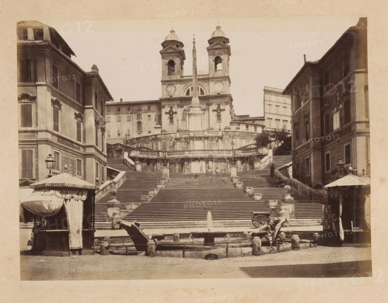 View of the Spanish Steps at the Piazza di Spagna in Rome, album page, photograph, This photo is part of an album., inscription: '463 SCALINATA DI PIAZZA DI SPAGNA', Rome, 1870 - c. 1895, photographer, paper, pasteboard, albumen print, albumendruk, height 200 mm x width 260 mm, square, circus, sloping street, street with steps or stairs, Piazza di Spagna, Spanish steps, A wide stone staircase rises between two multistory buildings, leading up to a terrace with balustrades and a church facade with twin bell towers and a tall obelisk in front. On either side of the lower steps are lamp posts and stone balusters, and a fountain basin with sculpted elements sits at the base of the stairs, with a small jet of water visible. Tented kiosks with decorative canopies stand near the buildings at the bottom of the steps, and shuttered windows and ornate window surrounds are visible on the flanking facades. The image has a sepia tone and shows architectural details such as cornices, pilasters, and ...