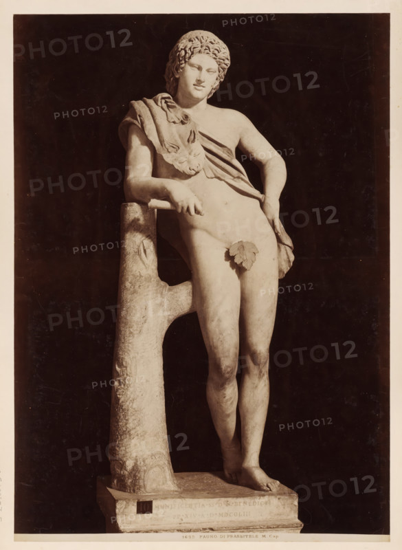 Sculpture of a faun, after Praxitiles, in the Capitoline Museums in Rome, 1683. Fauno di Prassitele M. Cap, album page, photograph, This photo is part of an album., inscription: '1683. Fauno di Prassitele M. Cap.', photographer: attributed to James Anderson, Capitoline Museums, after sculpture by anonymous, c. 1857 - c. 1875, after sculpture by, Rome, Attributed to, paper, albumen print, height 384 mm x width 275 mm, piece of sculpture, reproduction of a piece of sculpture, satyr(s) (in general), A photograph of a marble statue of a nude youth leaning against a rough, tree-like support, the figure shown from head to feet with curly hair and a relaxed facial expression, a draped cloth across one shoulder and torso with a lionhead detail on the cloth, an ornamental leaf placed over the groin, one arm resting on the support and the other hand touching the hip, the legs gently crossed at the ankles and the feet positioned on a rectangular plinth, the statue set against a dark background an...