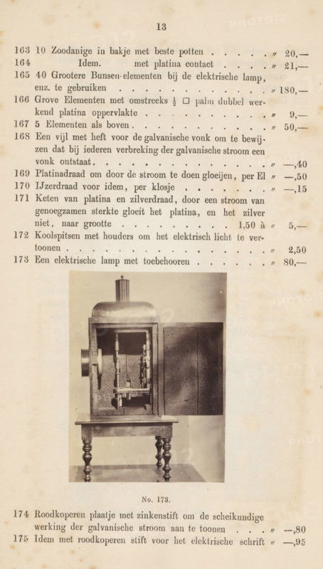 Electric lamp in a housing, photograph, page, number: 'No. 173.', photographer: Fredrich Wilhelm Funckler, Netherlands, c. 1857 - in or before 1867, paper, albumen print, height 76 mm x width 56 mm, Photo on page 13., electric lamp, A vertically oriented page with an aged, yellowed background showing a photograph of a mechanical apparatus mounted on a small ornate table; the apparatus has a boxlike frame with an open front revealing internal vertical and horizontal rods, cylindrical components, and a textured backing, topped by a rounded dome and a short cylindrical chimney, with a plain rectangular panel positioned to the right of the box; printed lines and columns of faint typed entries occupy the upper portion of the page above the photograph and there are additional printed entries below the photograph, some darker spots and foxing visible across the page.
