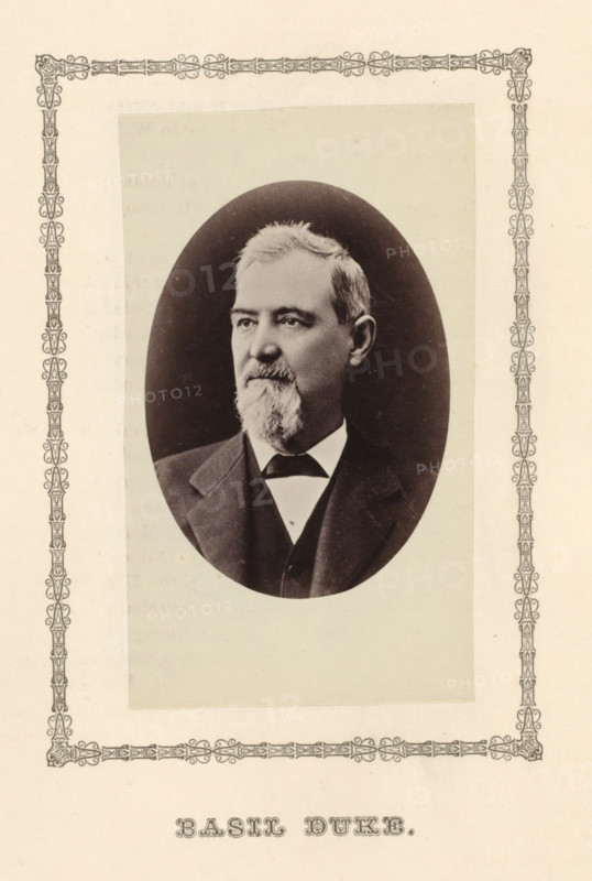 Basil Duke, photograph, page, c. 1876 - in or before 1881, photographer, paper, albumen print, height 95 mm x width 53 mm, adult man, A sepia-toned oval portrait of an older man with short hair and a full beard and mustache, wearing a dark suit jacket over a vest and a white shirt with a dark bow tie, set on a pale rectangular background framed by an ornate decorative border.