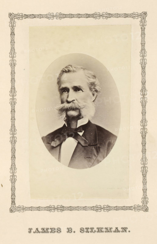 James B. Silkman, photograph, page, c. 1876 - in or before 1881, photographer, paper, albumen print, height 100 mm x width 58 mm, adult man, An oval black-and-white portrait of an older man with a full mustache and sideburns, wearing a dark suit jacket, a white shirt, and a bow at the collar, mounted on a pale rectangular background with a decorative ornate border around the page.