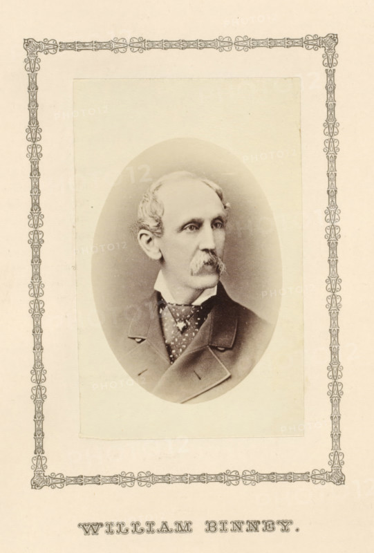 William Binney, photograph, page, c. 1876 - in or before 1881, photographer, paper, albumen print, height 91 mm x width 57 mm, adult man, A sepia-toned oval portrait of an older man is centered on a cream-colored page with a decorative border; the man has light hair combed back, a mustache, and a narrow face, and he is shown in three-quarter view looking to his left. He wears a high collared shirt, a patterned cravat or neckerchief, and a dark coat with wide lapels, with visible buttons and stitching. The oval portrait is mounted on a rectangular lighter panel that sits within an ornate narrow patterned frame that runs close to the page edges. The overall image has a vintage photographic appearance with soft shading around the figure and subtle paper texture.