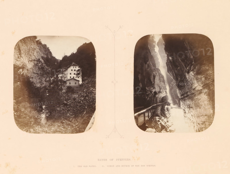 View of the gorge and the source of the thermal baths of Pfeffers, Baths of Pfeffers, photograph, page, inscription: 'II. Gorge and source of the hot springs', photographer: Stephen Thompson, Tamina, c. 1863 - in or before 1868, paper, albumen print, height 120 mm x width 83 mm, river, watering-place, spa, ravine, chasm, abyss, canyon (landscape with figures, staffage), A sepia-toned image with two rounded rectangular photographs side by side on a pale background, the left photograph showing a multi-story light-colored building nestled at the base of steep rocky cliffs with trees and vegetation surrounding it and a narrow stream or rocky path in the foreground, the right photograph depicting a narrow gorge with sheer rock walls, a wooden railing and pathway along one side, and a bright vertical area of water or mist cascading between the rock faces.