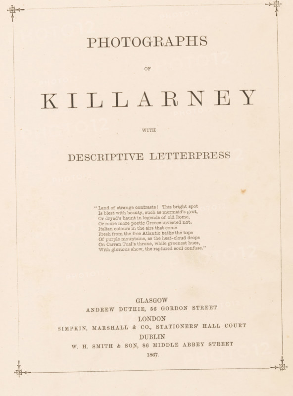 Photographs of Killarney with descriptive letterpress, book, annotation: 'SEPT, 1991', publisher: Andrew Duthie, Glasgow, publisher: Simpkin, Marshall, and Company, London, publisher: WH Smith & Son, Dublin, c. 1867, Leinster, pasteboard, paper, textile materials, printing, albumen print, color on cut, height 278 mm x width 215 mm x thickness 17 mm, A cream-colored page with a thin decorative border and small floral corner ornaments, featuring large spaced dark serif characters centered near the top, smaller centered dark serif lines below, a short centered stanza of narrow dark serif lines in the upper middle, and additional centered dark serif lines lower on the page, with subtle paper texture and a small brown spot near the right center.