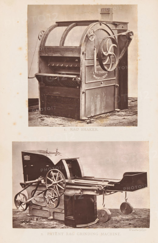 View of a rag grinding machine, 2. Patent Rag Grinding Machine, page, photomechanical print, photographer: Appleton & Co., cliché maker: Woodbury Permanent Photographic Printing Company, Bradford (England), c. 1871 - in or before 1876, paper, Woodburytype, Woodburytypepie, height 73 mm x width 115 mm, machine driven by human or animal power, A sepia-toned photograph shows two large industrial machines arranged vertically on a single sheet. The top machine is a boxy apparatus with a curved upper frame, a slotted front opening with a perforated tray, and a large side wheel connected to a belt and pulley system; the surface shows worn metal and wood textures and traces of dirt on the floor beneath. The bottom image depicts a more elongated machine with multiple large spoked wheels and gears, a flat extended tray or chute, suspended circular weights, and a rectangular enclosed section at the front; the metal parts show patina and the ground beneath both machines is uneven and slightly dirt...
