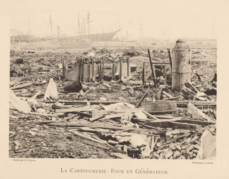 Remains of the oven and generator of a munitions factory that exploded in Oosterweel near Antwerp in 1889, La cartoucherie. Four et générateur, page, photomechanical print, number: '17', photographer: Henri Colon, Oosterweel, cliché maker: anonymous, Belgium, printer (person): J. Maes (possibly), Antwerp, 1889, printer (person), paper, collotype, light pressure, height 165 mm x width 230 mm, Image on page 17., ruin of a building, architecture, Explosion of a munitions factory in Oosterweel in 1889, A wide scene of debris and broken wooden planks scattered across uneven ground with mud and rubble; in the foreground torn cloth and splintered beams lie mixed with fragments of construction materials and a large upturned barrel; toward the middle a ruined circular brick structure held by vertical metal supports sits among piles of broken boards and loose bricks; nearby are upright wooden frames and a tall cylindrical metal tank with rivets and attached fittings standing amid more wreckage; ...