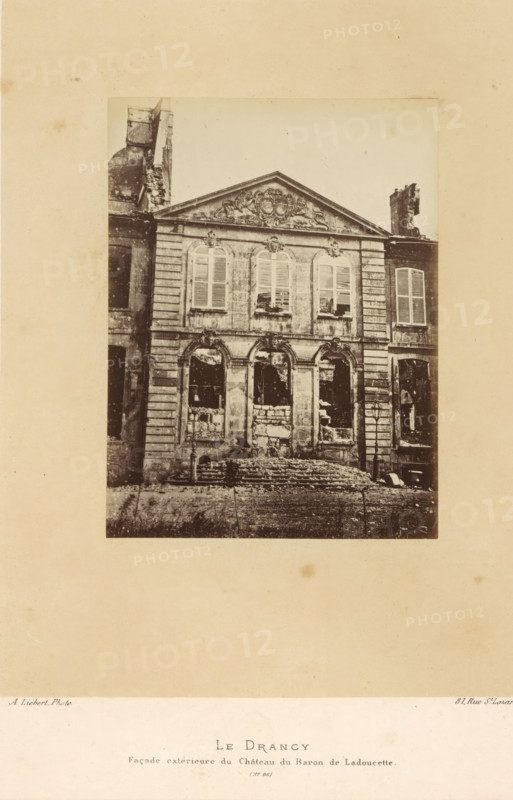 View of Baron de Ladoucette's villa in Drancy after the destruction by the Paris Commune, Le Drancy. Façade extérieure du Château du Baron de Ladoucette, photograph, page, address: '31, Rue St. Lazare', number: '(No. 86)', photographer: Alphonse-Justin Liébert, Drancy, 1871 - 1872, Alphonse-Justin Liébert, photographer, paper, albumen print, albumendruk, height 131 mm x width 99 mm, villa, ruin of a building, architecture, Paris Commune (1871), A sepia-toned photograph of a stone building with a decorative triangular pediment atop its facade, showing ornate sculpted details and a row of three arched windows on the upper level with shutters, and three larger arched openings on the ground level with visible damage and rubble in front; flanking sections of the building show vertical stonework and additional windows, one side with a broken chimney structure, and a lamp post near the right entrance, all centered on a plain light background with a narrow border around the image.