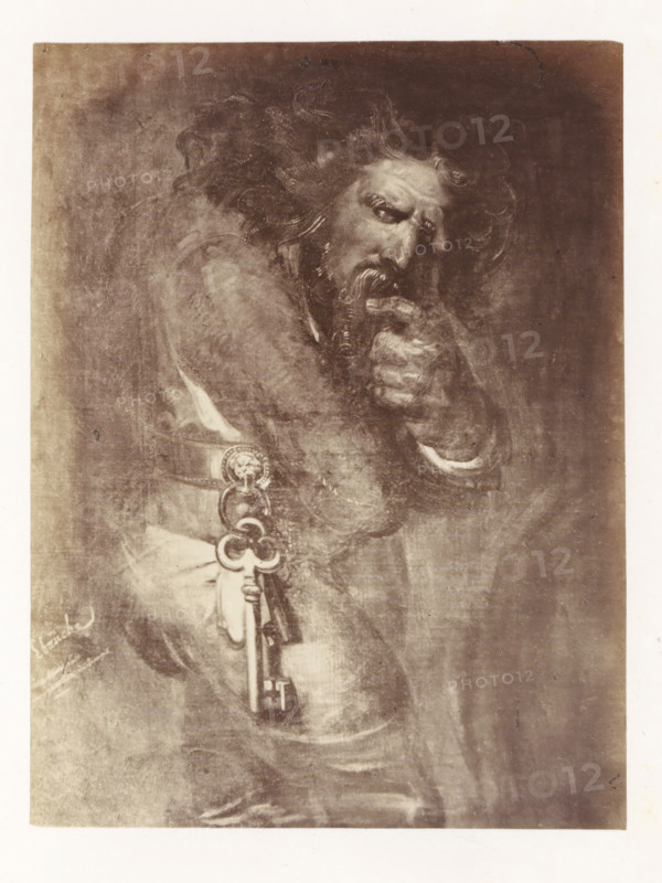 Photo reproduction of Quasimodo by Antoine Wiertz, photograph, reproduction, page, check stamp: 'SOCIÉTÉ ROYALE BELGE DE PHOTOGRAPHIE, 69, RUE KEYENVELD, BRUXELLES', photographer: Edmond Fierlants, after painting by Antoine Joseph Wiertz, c. 1863 - in or before 1868, paper, albumen print, albumendruk, height 151 mm x width 115 mm, male literary characters (QUASIMODO), A sepia-toned image of an older bearded man shown from the waist up, wearing a cloak with flowing hair and a furrowed brow, his hand raised to his mouth with fingers near his lips, a large ornate key hanging from his belt with decorative rings and a circular medallion, the background textured and darker around the figure, the image framed by a light border.
