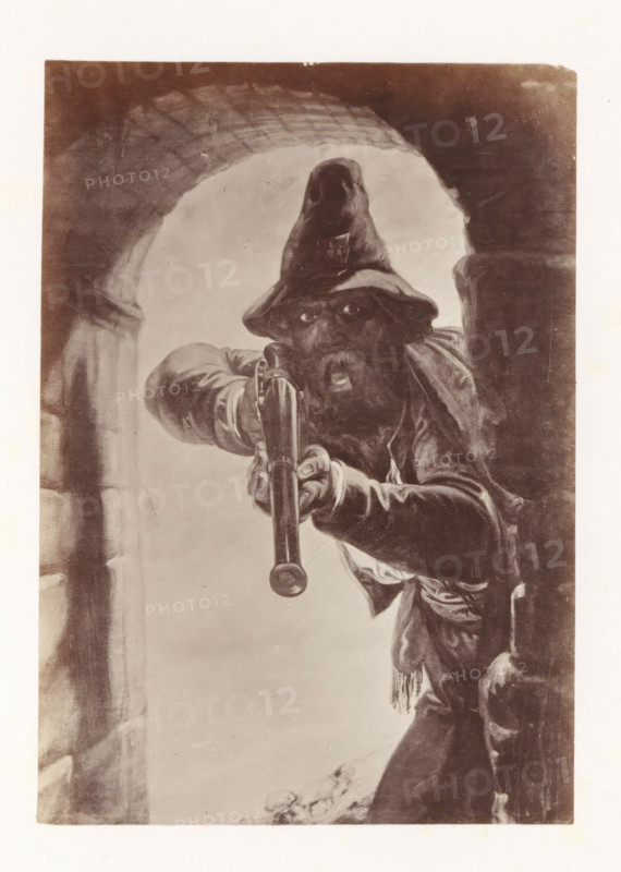 Photo reproduction of Calabrian highwayman by Antoine Wiertz, photograph, reproduction, page, check stamp: 'SOCIÉTÉ ROYALE BELGE DE PHOTOGRAPHIE, 69, RUE KEYENVELD, BRUXELLES', photographer: Edmond Fierlants, after painting by Antoine Joseph Wiertz, c. 1863 - in or before 1868, paper, albumen print, albumendruk, height 150 mm x width 105 mm, robber, A sepia-toned illustration of a bearded man wearing a floppy hat and heavy clothing leaning forward through a stone archway while pointing a long-barreled firearm directly outward, his eyes visible beneath the hat, one hand gripping the barrel and the other on the stock, with folds and tassels on his garments and a partially visible stone wall beside him.