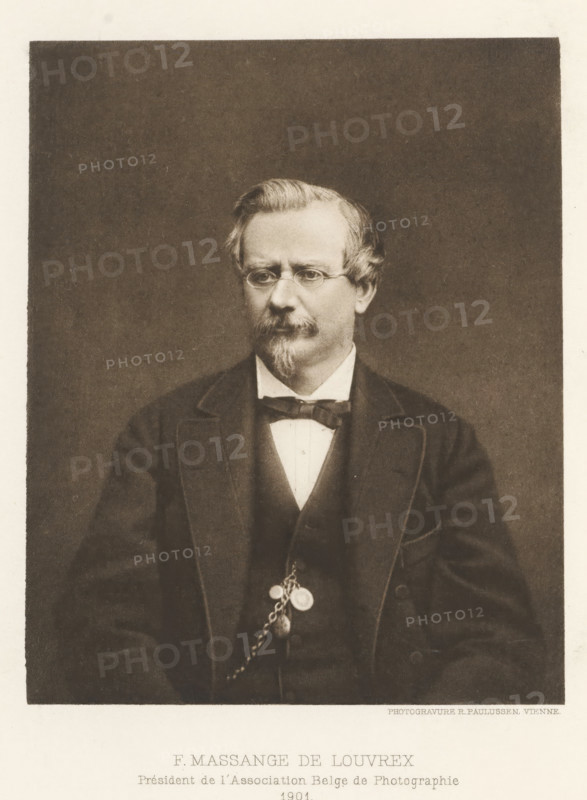 F. Massange-de Louvrex, Portrait of Ferdinand Massange-de Louvrex, page, photomechanical print, inscription: 'Président de l'Association Belge de Photographie, 1901', maker: Richard Paulussen, c. 1897 - in or before 1902, Richard Paulussen, paper, photoaquatint, height 122 mm x width 99 mm, Print two pages before page 224., Person, Ferdinand Massange - the Louvrex, historical persons, adult man, A sepia-toned portrait of a middle-aged man seated against a plain dark background, wearing round spectacles and a neatly trimmed mustache and goatee, his hair combed to the side with a slight wave; he is dressed in a dark suit jacket over a waistcoat and white shirt with a bow tie, and a pocket watch chain with attached fobs hangs from his waistcoat.