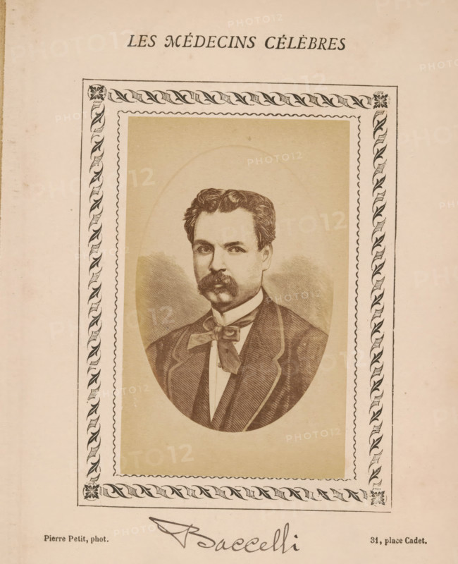 Photo reproduction of a portrait of Guido Baccelli, photograph, reproduction, page, annotation: 'Paracelse', number: '78', inscription: 'Publication de la Revue de literature médicale, du docteur Felix Bremond, 20, Passage Saulnier, 4e année.) - No.', photographer: Pierre Petit, after design by anonymous, c. 1871 - c. 1879, paper, albumen print, height 81 mm x width 51 mm, Person, Guido Baccelli, historical persons, adult man, A sepia-toned printed portrait of a man with wavy hair and a thick mustache, shown waist-up inside an oval frame; he wears a jacket with a visible lapel, a shirt with a high collar, and a wide bow at the neck. The oval portrait is set on a rectangular beige background surrounded by an ornate border with a repeating leaf-and-scroll pattern and a scalloped inner edge. The page has a light cream color and shows slight age spotting and wear.