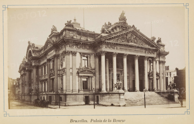 Brussels. Palace of the Stock Exchange, View of the Brussels Stock Exchange, photograph, page, Brussels, c. 1875 - c. 1880, photographer, paper, albumen print, height 98 mm x width 172 mm, Exchange, Stock Exchange, A sepia-toned photograph of a large neoclassical stone building with a wide staircase leading to a colonnaded portico topped by a triangular pediment carved with sculpted figures, flanked by ornate cornices and statues on the roofline; tall fluted columns stand at the entrance, and sculpted lion-mounted figures sit on pedestals at the base of the stairs; the façade features tall arched windows, decorative reliefs, pilasters, and elaborate stone ornamentation; a narrow street runs along the left side with horse-drawn carriages and a few street lamps, while smaller buildings are visible in the background to the right.