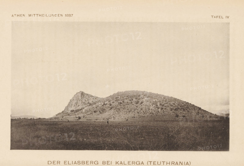 View of a mountain, Der Eliasberg bei Kalerga (Teuthrania), page, photomechanical print, inscription: 'Athen Mittheilungen 1887 Tafel IV', c. 1881 - in or before 1886, paper, collotype, photoprint, height 101 mm x width 179 mm, Print two pages after page 148., mountains, A sepia-toned photograph showing a gently sloping rocky hill with a steeper craggy peak on one side, covered in patches of low vegetation and scattered shrubs; a flat open plain in the foreground with sparse grassy growth and a solitary small figure standing near the center, and a pale sky above occupying most of the upper area.