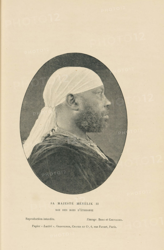 Sa Majesté Ménélik II, Roi des Rois d'Éthiopie, Portrait of Menelik II, page, photomechanical print, inscription: 'Reproduction interdite., Papier &lt, Lustré &gt, . Grosvenor, Chater et Co, 6, rue Favart, Paris.', cliché maker: Berg et Chevalier, c. 1891 - in or before 1896, Berg et Chevalier, photographer, cliché maker, paper, autotype, zincogravure, height 112 mm x width 85 mm, Person, Menelik II, historical persons, emperor, A sepia-toned oval portrait of a person in profile facing right, wearing a light headwrap tied at the back with a long tail, a textured dark garment, and a beaded or ornate necklace; the portrait is centered on a pale page with faint paper texture and small printed lines of text below the oval.