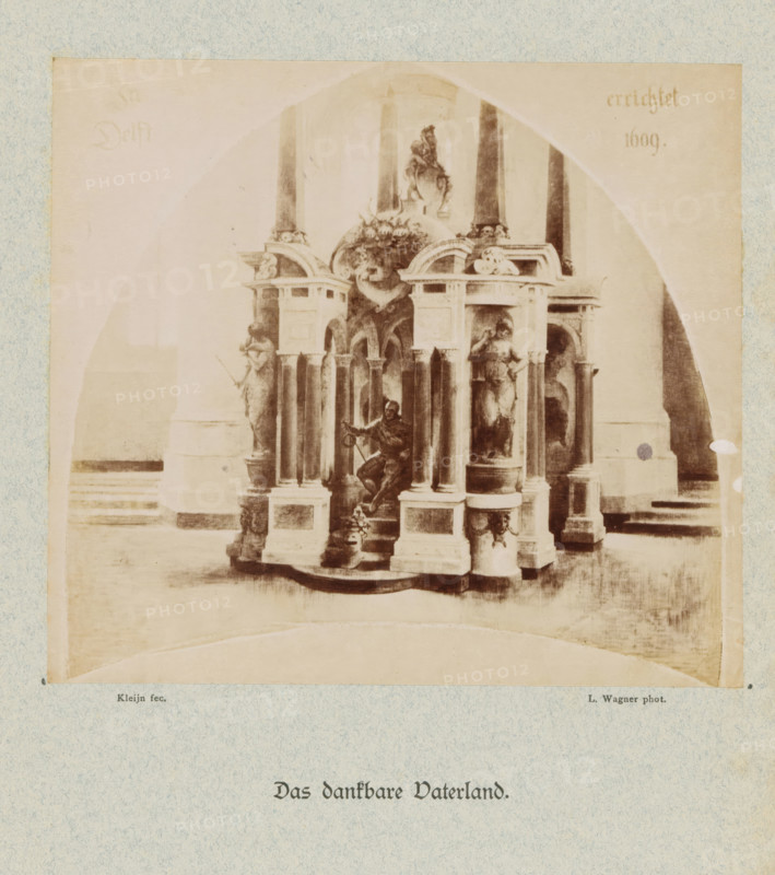 Das dankbare Vaterland, Photographic reproduction of Het dankbare Vaderland by Laurens Lodewijk Kleijn, photograph, reproduction, This photo is part of a cover with eight photos on eight sheets and two text sheets., photographer: L. Wagner, after painting by Laurens Lodewijk Kleijn, c. 1879 - in or before c. 1884, paper, albumen print, height 146 mm x width 164 mm, Person, Willem I (Prince of Orange), grave, tomb, Delft, Nieuwe Kerk (Delft), A faded monochrome photograph shows an ornate stone monument with columns and sculpted figures under a large archway, flanked by tall vertical pillars and set on a stepped base; the monument includes seated and standing statues, decorative reliefs and rounded pedestals, and a central kneeling figure holding an object, all rendered in soft sepia tones against a lighter background.