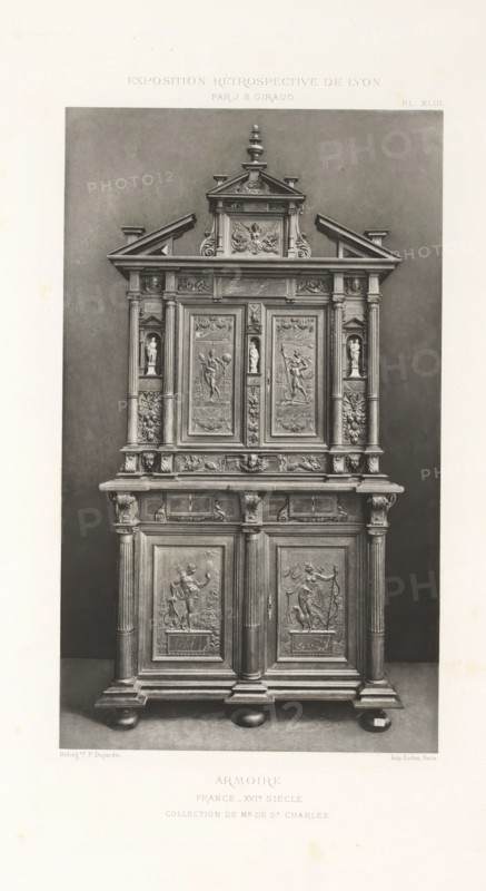 16th-century French wooden cabinet, at the Exposition Rétrospective of 1877 in Lyon, France, photomechanical print, This print is part of a cover with 79 prints on 54 sheets and 65 text sheets., inscription: 'ARMOIRE, FRANCE_XVIe SIÈCLE, COLLECTION DE Mr DE St CHARLES.', inscription: 'EXPOSITION RÉTROSPECTIVE DE LYON, PAR JB GIRAUD.', number: 'PL. XLIII.', photographer: Jacques Garcin, Lyon, cliché maker: Dujardin, printer (person): Imprimerie Eudes, Paris, 1877 - 1878, printer (person), paper, photoaquatint, height 463 mm x width 313 mm, ornamental cupboard (wood and other phytogenic material), A tall ornate wooden cabinet stands against a plain dark background, featuring an upper section with a triangular pediment topped by a finial and intricate carved detailing including scrollwork and a central relief panel, flanked by small pilasters and recessed niches each holding a small sculpted figurine; below this the central doors display carved panels with figural scenes framed by decorat...