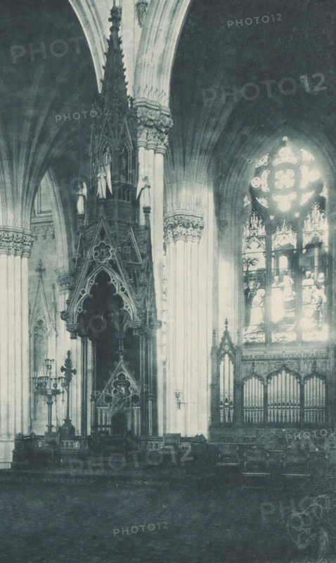 Saint Patricks Cathedral, New York, Altar and lectern in Saint Patrick's Cathedral in New York, page, photomechanical print, inscription: 'Altar, Bishops Throne', cliché maker: Lakeside Press, publisher: Haskell & Post Publishers, c. 1881 - in or before 1886, Lakeside Press, Haskell & Post Publishers, photographer, cliché maker, publisher, paper, collotype, photoprint, height 300 mm x width 425 mm, altar, bishop's throne, North America, Saint Patrick's Cathedral (New York), A rotated photograph of an ornate interior showing tall arched ceilings and elaborate carved columns topped with decorative capitals, a large circular stained glass window with bright panes, patterned vertical windows, and an elevated carved wooden structure with pointed arches and intricate tracery above a darkened platform area; pale walls and draped curtains form the backdrop and a wide pale border surrounds the image.