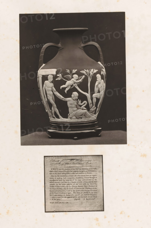 Letter and the Wedgwood replica of the Portland Vase, photograph, page, photographer: Joseph Cundall, c. 1868 - in or before 1873, paper, carbon print, height 361 mm x width 270 mm, Photo on second unnumbered page after page viii., letter, envelope, container of ceramics: jar, jug, pot, vase, A photograph of a decorative vase with two curved handles on a dark background, placed on a round base and a flat textured surface; the vase shows a raised classical relief scene depicting human figures in various poses among stylized trees, one reclining figure, one seated figure with a contemplative pose, another standing figure reaching toward the reclining figure, and a winged cherub-like figure above them; the vase body has a smooth dark finish contrasting with the lighter relief elements; the image is mounted on a pale sheet with scattered small brown spots and a separate rectangular block of printed material below the photograph.