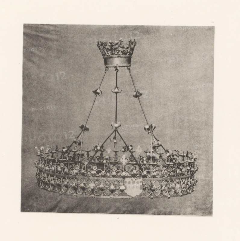 Wrought-iron chandelier from St. Peter's Church in Bastogne, displayed at an exhibition on religious objects from the Middle Ages and Renaissance in 1864 in Mechelen, page, photomechanical print, number: '-56', number: '16', photographer: Joseph Maes, Mechelen, clichémaker: Simonau & Toovey, Antwerp, 1864 - in or before 1866, Joseph Maes, Simonau & Toovey, photographer, clichémaker, Mechelen (heerlijkheid), paper, photolithography, height 168 mm x width 169 mm, chandelier, candelabrum, Period, 1864, A grayscale photograph of an ornate metal crown suspended by thin chains from a decorative circular support, showing a detailed upper band with repeating circular motifs and floral elements, small bowls or candle holders attached to the vertical supports, a smaller crown-like piece at the top with a textured leafy rim, and a plain backdrop behind the suspended object.