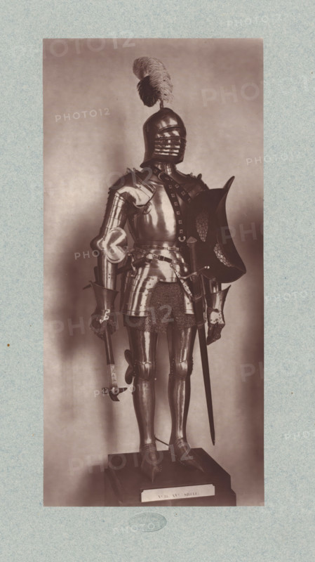 15th-century armor with sword and axe from the army of Charles VII of France, from the collection of the Musée d'Artillerie in Paris, photomechanical print, This print is part of a cover with 36 prints, a title page and a list of images., check stamp: 'PHOTOGLYPTIE, LEMERCIER ET Cie, PARIS', Paris, cliché maker: Lemercier & Cie., c. 1877 - in or before 1882, Lemercier & Cie., photographer, cliché maker, paper, Woodburytype, Woodburytypie, height 272 mm x width 128 mm, armor, hacking and thrusting weapons, A full suit of polished metal armor stands upright on a rectangular display base against a plain background, the armor including a closed helmet with horizontal visor slits and a large feather plume on top, articulated shoulder plates, gauntleted hands, a breastplate with decorative straps, a chain skirt beneath the waistplate, articulated tassets and greaves, and pointed sabatons; one hand holds a hammer-like weapon while the other rests near a sword suspended at the hip and a curved...