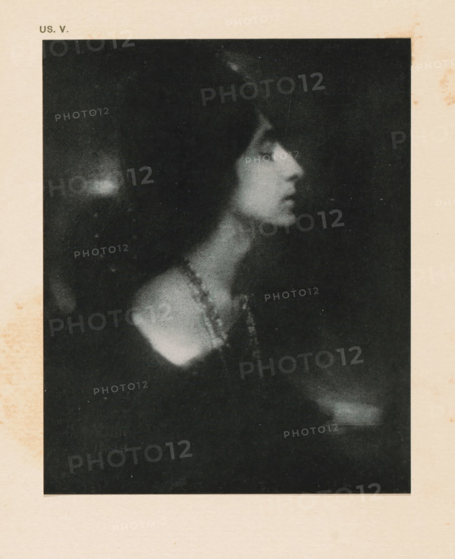 Portrait of an unknown woman, page, photomechanical print, inscription: 'US. V.', inscription: 'La bella by Eduard J. Steichen', photographer: Edward Steichen, cliché maker: anonymous, c. 1900 - in or before 1905, paper, two-color autotype, height 137 mm x width 111 mm, historical persons - BB - woman, A grainy black and white portrait of a woman in profile showing her head, neck, and shoulder against a dark background, with her hair dark and framing her face, her eyes closed, her lips slightly parted, and a beaded necklace draped around her neck and over her shoulder.