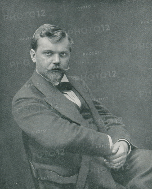 Portrait of an unknown man, page, photomechanical print, inscription: 'Das Atelier des Photographen.', monogram: 'LEIPZIG, S G', photographer: Jacob Hilsdorf, Bingen, cliché maker: unknown, Leipzig, printer (person): Wilhelm Knapp, Halle an der Saale, c. 1895 - in or before 1900, printer (person), Rhineland-Palatinate, Saxony-Anhalt, Saxony, paper, autotypie, height 175 mm x width 140 mm, historical persons, A black and white portrait of a seated man shown from the waist up, wearing a dark suit jacket and vest with a white shirt and a bow tie, with one arm resting across his body and his hands clasped together in his lap; he has short hair styled with a wave, a mustache curled at the ends, and a pointed beard, and he looks directly toward the camera against a plain dark background.