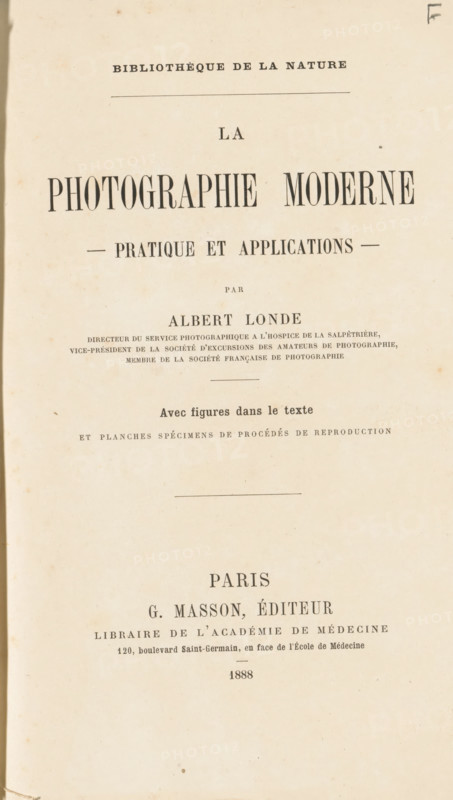 La photographie moderne : pratique et applications, book, number: '5562', date: 'AUG 1995', number: '1800', bookplate: 'H. van Ommeren, Paramaribo - Suriname', publisher: Georges Masson, Paris, 1888, textile materials, pasteboard, biological material, paper, linen (material), leather, transparent paper, printing, collo-autotypie, photoaquatint, collotype, height 252 mm x width 170 mm x thickness 30 mm, A vertically oriented aged paper page with a narrow dark margin on the left, displaying multiple lines of printed text in varying large and small serif fonts, centered across the page with horizontal dividing lines and some small decorative marks, the paper showing light brown foxing spots and slight discoloration around the edges.