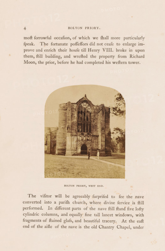 West side of Bolton Priory at Bolton Abbey, Bolton Priory, West end, photograph, page, photographer: William Russell Sedgfield, Bolton Abbey, c. 1857 - in or before 1862, Yorkshire, Wharfedale, paper, albumen print, height 72 mm x width 62 mm, Photo on page 4., ruin of church, monastery, A sepia-toned photograph shows the stone west front of a ruined priory with a large arched entrance and tall ornate window openings above, flanked by thick vertical buttresses; two small human figures stand on the lawn in front of the building, and trees appear at the right edge of the image, all set against a pale background on an aged paper page.