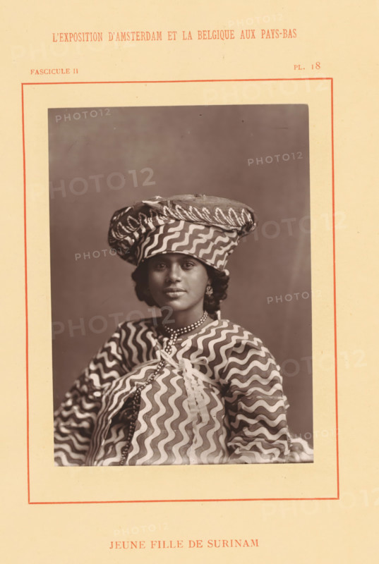 Jeune fille de Surinam, Portrait of probably Wilhelminia van Ede, page, photomechanical print, inscription: 'Fascicule II, PL. 18', photographer: attributed to Photographie Française (Amsterdam), cliché maker: anonymous, c. 1878 - in or before 1883, Attributed to, paper, Woodburytype, height 138 mm x width 100 mm, Person, Wilhelminia van Ede, historical persons - BB - woman, World Exhibition 1883 (Amsterdam), A sepia portrait of a young woman centered on a pale bordered page, wearing a patterned headwrap and matching garment with bold wavy stripes, a beaded necklace, earrings, and a calm facial expression, photographed against a plain darker backdrop.