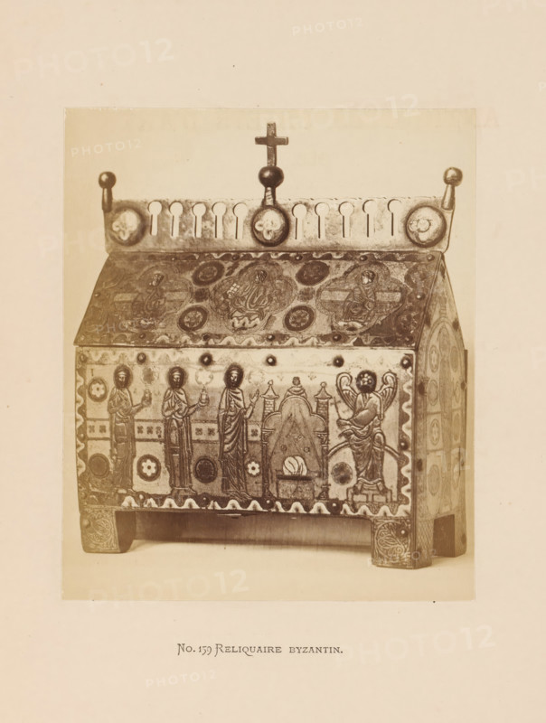 Byzantine reliquary in the form of a sarcophagus, photograph, page, inscription: 'No. 159. Reliquaire Byzantin', photographer: Anselm Schmitz, c. 1871 - in or before 1876, paper, albumen print, height 125 mm x width 105 mm, sarcophagus, relics (and reliquaries), A photograph shows a rectangular ornate box with a sloped lid, raised on short carved legs, covered in decorative panels and medallions; the lid top has circular motifs and a frieze with rounded cutouts topped by a central finial with a small cross and spherical knobs at the corners; the front panel displays standing robed figures, circular ornaments, and a scene with an arched element and a seated winged figure, all rendered in a stylized carved and inlaid manner, with patterned borders along the edges.