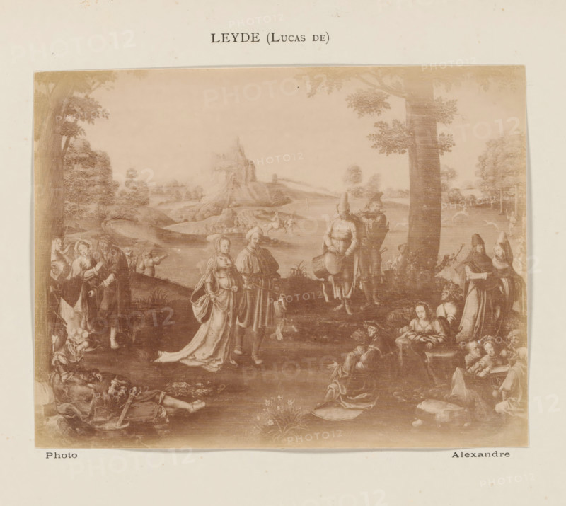 Photo reproduction of The Dance of Mary Magdalene by Lucas van Leyden, photograph, reproduction, page, inscription: 'Leyde (Lucas de)', photographer: Alexandre, after print by Lucas van Leyden, c. 1878 - in or before 1883, Lucas van Leyden, after print by, paper, albumen print, albumendruk, height 100 mm x width 130 mm, life of St. Mary Magdalene before her conversion, eg dancing, hunting, A faded sepia-toned reproduction of a detailed landscape scene centered on a group of people in period clothing gathered under trees with rolling hills and a distant rocky outcrop in the background, showing figures standing, sitting, and reclining; some figures appear near a tree trunk at right while others form small clusters across the foreground, with one pair in flowing garments near the center, a drummer-like figure and another playing a wind instrument nearby, scattered small animals and pastoral elements in the midground, and ornamental foliage and flowering plants in the lower area, all borde...