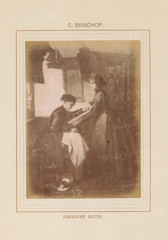 Photo reproduction of Dimanche Matin by Christoffel Bisschop, Dimanche Matin, photograph, reproduction, page, inscription: 'C. Bisschop', after painting by Christoffel Bisschop, c. 1878 - in or before 1883, photographer, paper, albumen print, height 134 mm x width 98 mm, adult man, painting, drawing and the graphic arts, A sepia-toned framed illustration shows two women indoors near a window and a wooden panel; one woman is seated and leaning over a large book or album held by the standing woman, both wearing period dresses and head coverings, the seated woman with a light cloth draped over her lap and the standing woman holding a cup, a small cat is on the floor near a saucer, and the scene is bordered by decorative lines on a cream-colored page.