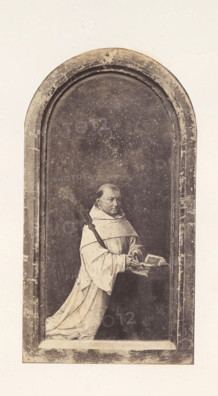 Photo reproduction of Robrecht de Clercq, abbot of Ter Duinen, photograph, reproduction, page, photographer: Edmond Fierlants, after painting by anonymous, publisher: C. Muquardt, Brussels, c. 1856 - in or before c. 1861, paper, albumen print, albumendruk, height 378 mm x width 206 mm, monk(s), friar(s), one person praying, A vertical rectangular image with an arched, recessed panel occupying most of the frame, showing a monochrome scene of a robed figure kneeling on a ledge inside the arch. The figure wears a light-colored hooded robe with long flowing sleeves and holds an open book resting on a small lectern or stand, one hand touching the pages. A long staff or rod with a textured top rests against the figure’s shoulder and extends upward. The background inside the arch is dark and speckled, with visible wear and mottling, while the arch and surrounding border show scratches, scuffs, and spots of discoloration. The outer margins are light and plain, contrasting with the darker inter...