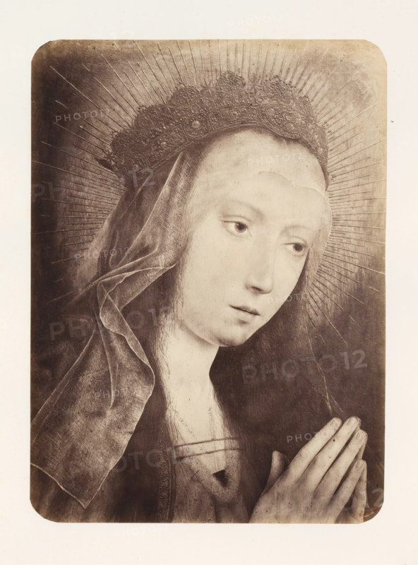 Photo reproduction of Mary in prayer by Quinten Massijs, photograph, reproduction, page, photographer: Edmond Fierlants, after painting by Quinten Massijs (I), publisher: C. Muquardt, Brussels, c. 1856 - in or before c. 1861, paper, albumen print, albumendruk, height 371 mm x width 272 mm, Mary praying, A sepia-toned portrait of a young woman shown from the shoulders up with a slightly bowed head and hands held together in a praying position, wearing a dark veil and an ornate crown with radiating lines behind it, her face is pale with downcast eyes and a calm expression, delicate fingers with visible knuckles are clasped together, the veil shows soft folds and texture, the crown has detailed embellishments and the background is plain with faint radial lines extending outward.