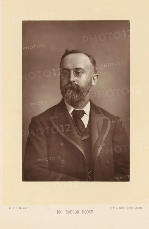 Dr. Robson Roose, Portrait of Edward Charles Robson Roose, page, photomechanical print, inscription: '57 & 61, Elbury Street, London.', photographer: Downey, William & Daniel, London, cliché maker: anonymous, c. 1882 - in or before 1892, paper, Woodburytype, height 140 mm x width 93 mm, Person, Edward Charles Robson Roose, physician, doctor, A sepia portrait of a middle-aged man shown from the chest up, wearing a dark double-breasted jacket with wide lapels and a waistcoat beneath, a white shirt collar and a patterned tie; he has a full beard and mustache, short hair with a small wave at the top, round eyeglasses, and a neutral facial expression, set against a plain softly shaded background with a light border around the photograph.