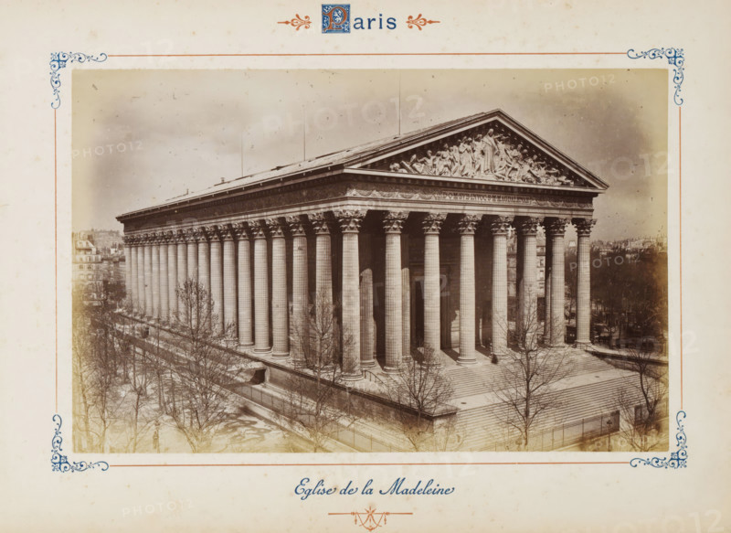 Interior of the Dôme des Invalides in Paris, with a view of the tomb of Napoleon Bonaparte, Tombeau de Napoléon 1er (Hôtel des Invalides), photograph, page, number: '36', Dôme des Invalides, c. 1879 - c. 1889, photographer, Paris, paper, albumen print, height 188 mm x width 120 mm, interior of church, grave-building, monumental tomb, A sepia-toned photograph shows a large neoclassical building with a wide flight of stone steps leading to a colonnaded portico; the façade features tall fluted columns with ornate capitals supporting an entablature and a triangular pediment adorned with sculpted figures. Leafless trees and bare branches are visible in the foreground along a paved promenade and fenced edge, while buildings and rooftops appear in the background on either side. The image is bordered by a decorative frame with corner flourishes and ornamental motifs at the top and bottom.