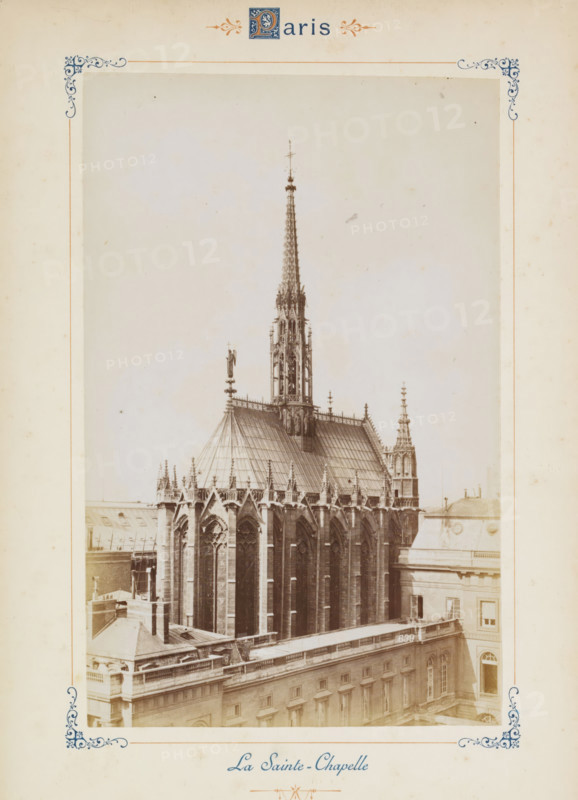 View of the Sainte-Chapelle in Paris, La Sainte-Chapelle, photograph, page, number: '639', Paris, c. 1879 - c. 1889, photographer, paper, albumen print, albumendruk, height 188 mm x width 120 mm, façade (of house or building), church (exterior) - QQ - small church, chapel, Sainte-Chapelle (Paris), A sepia-toned photograph centered on a Gothic chapel roof and spire, showing ornate stonework, pointed arches, tall narrow windows, decorative pinnacles, flying buttresses, and a slender, intricately detailed spire rising from the roof; surrounding the chapel are adjacent building rooftops with balustrades, flat roof surfaces, and rectangular windows; the image is framed by a decorative border with corner flourishes and ornamental motifs on a pale background.