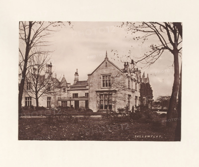 Gallowflat, photograph, page, photographer: Thomas Annan, Rutherglen, c. 1868 - in or before 1878, paper, carbon print, height 115 mm x width 160 mm, rural housing, eg country-house, villa, cottage, façade (of house or building), A sepia-toned photograph of a large stone house with steep gables and multiple chimneys, framed by tall leafless trees whose branches extend across the sky, a foreground of dark grass and low shrubs, and windows and architectural details visible on the building's facade.