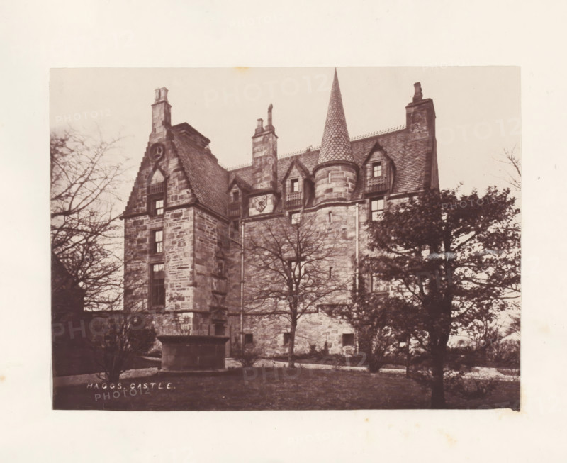 Haggs Castle, photograph, page, photographer: Thomas Annan, Glasgow, c. 1868 - in or before 1878, paper, carbon print, height 115 mm x width 160 mm, rural housing, eg country-house, villa, cottage, façade (or house or building), A sepia-toned photograph of a stone castle facade with steep gabled roofs, chimneys, and a tall conical turret covered in patterned tiles, framed by bare-branched trees and evergreens in the foreground, with stone walls showing visible blocks and small windows set into dormers and vertical bays.