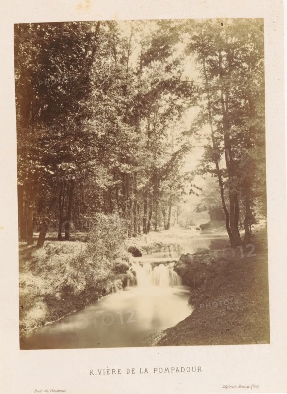 Rivière de la Pompadour, River in the Bois de Vincennes, Bois de Vincennes, photograph, page, photographer: Ildefonse Rousset, c. 1861 - in or before 1866, Paris, paper, albumen print, height 173 mm x width 132 mm, river, public gardens, park, A sepia-toned photograph of a wooded scene showing a calm narrow river flowing toward the foreground with a small cascading drop over rocks, tree trunks along both banks, dense leafy canopies overhead filtering light, grassy and brush-covered riverbanks, reflections of trees in the water, and a soft bright area in the distance beyond the trees.
