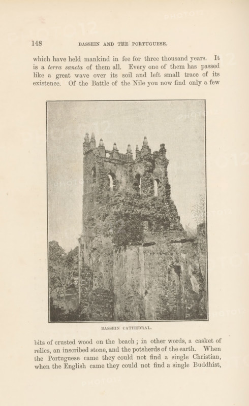 Bassein cathedral, page, photomechanical print, Pathein, cliché maker: Lemercier & Cie., Paris, c. 1883 - in or before 1893, photographer, paper, photochemical processes, height 115 mm x width 82 mm, ruin of church, monastery, A sepia-toned photograph framed on a page shows a tall, weathered stone ruin rising from a rocky base, with ornate battlements and arched window openings near the top and rough, crumbling masonry below, vegetation growing around and on parts of the structure, and faint foliage visible at the sides.