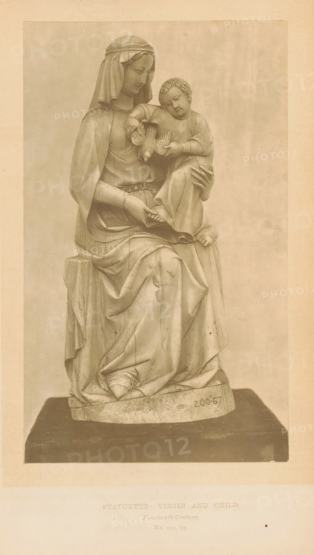 Statuette, Virgin and Child, page, photomechanical print, number: 'No. 200 '67.', inscription: 'Fourteenth Century.', London, c. 1867 - in or before 1872, paper, Woodburytype, height 166 mm x width 100 mm, sculpture, Madonna: ie Mary with the Christ-child, A monochrome photograph of a seated draped female figure wearing a head covering, holding a smaller child figure on her lap; both figures are carved with detailed folds in their garments and the child holds a small bird, the woman's hands supporting the child and resting on the drapery, the sculpture is positioned on a rectangular base with visible wear and texture, and the image is bordered by a lighter margin.