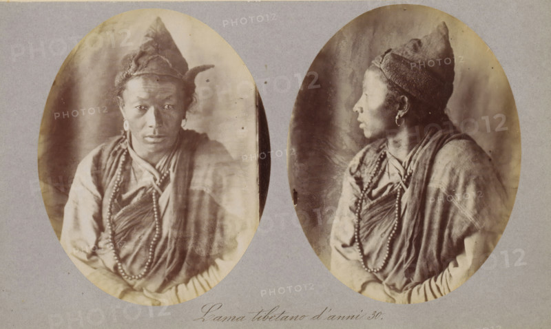 Two portraits of a Tibetan lama, Lama tibetano d'anni 30, photograph, page, photographer: Paolo Mantegazza, Tibet, c. 1881 - in or before 1886, Paolo Mantegazza, photographer, paper, albumen print, height 151 mm x width 241 mm, adult man (side view, profile), adult man (front view), priest, Hinduism, Buddhism, Jainism, Two oval sepia portraits of the same person are mounted on a grey background; in the left portrait the person faces forward with a neutral expression, wearing a pointed cap with a textured band, circular earrings, draped layered clothing, and a long beaded necklace, while in the right portrait the person is shown in profile facing to the side wearing the same cap, earrings, layered garments, and beads, with hands resting in front and a soft, mottled backdrop behind both images.